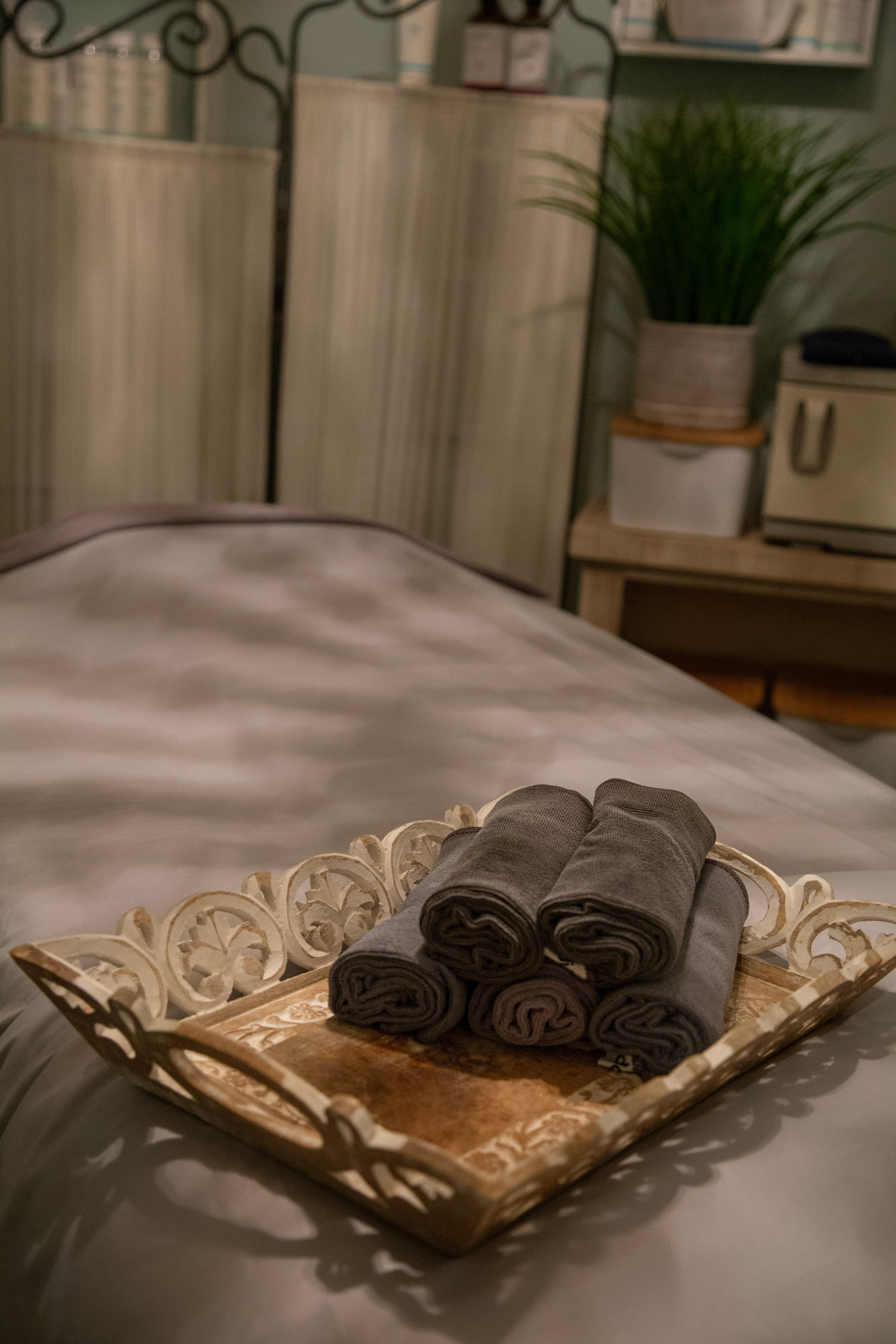 Rolled towels on a carved wooden tray atop a massage table