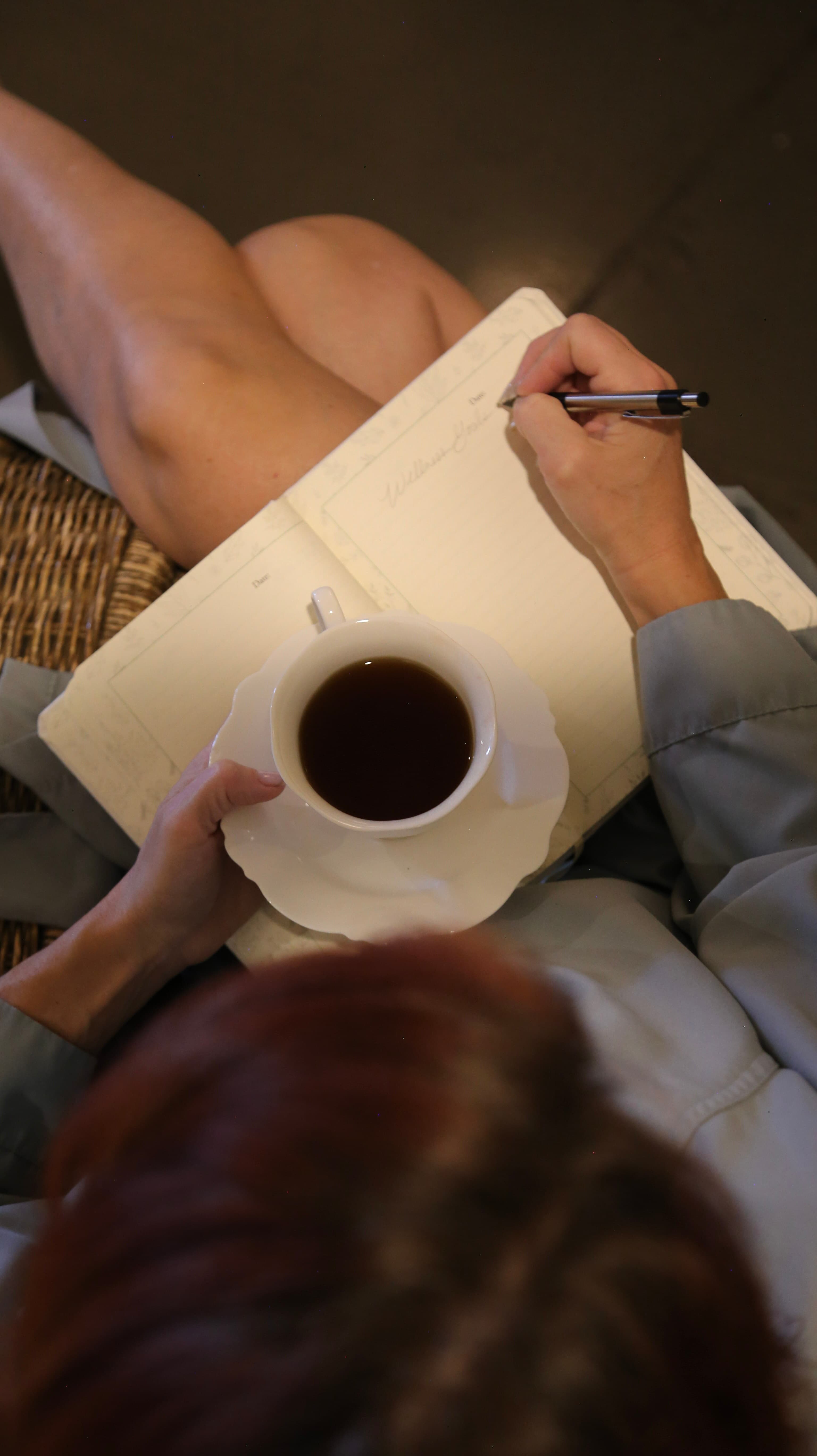 Overhead view of a robed client journaling with a cup of tea